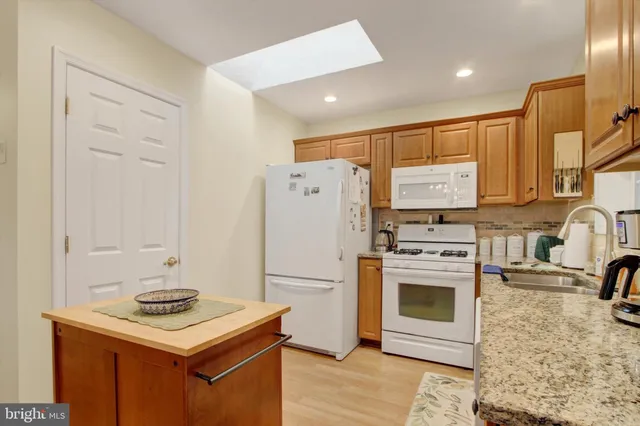 a kitchen with stainless steel appliances granite countertop a refrigerator sink stove and oven