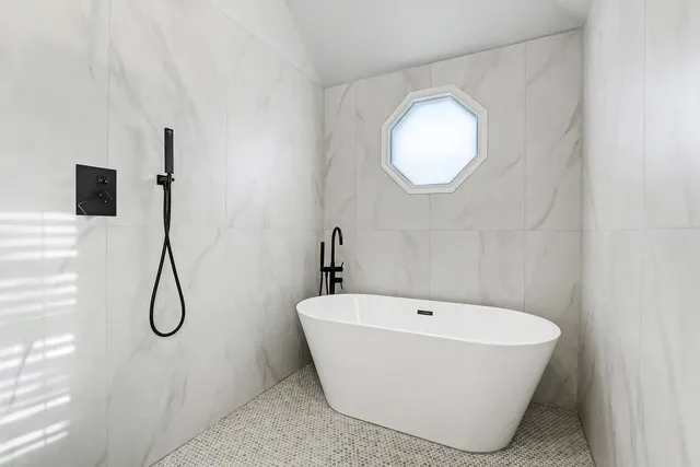 a bathroom with a white tub a mirror and window