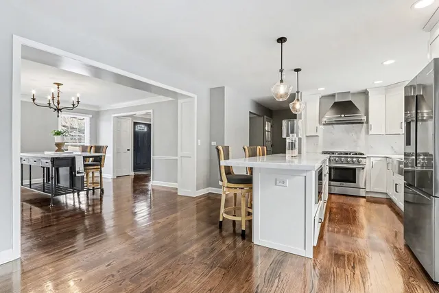 a kitchen with stainless steel appliances granite countertop a refrigerator a stove top oven a sink dishwasher and a dining table with wooden floor