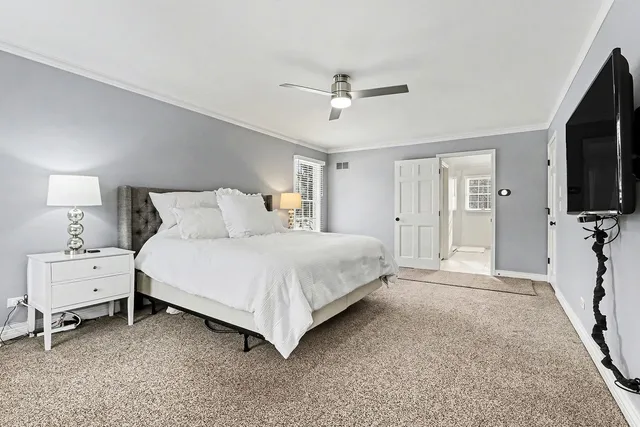 a spacious bedroom with a bed and a flat tv screen on dresser