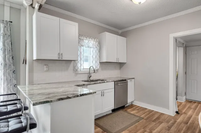 a kitchen with stainless steel appliances granite countertop a stove a sink dishwasher and a refrigerator with wooden floor