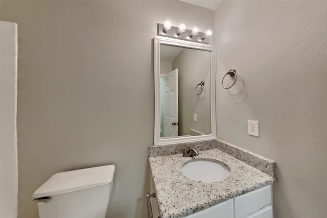 a bathroom with a granite countertop sink a toilet and a mirror