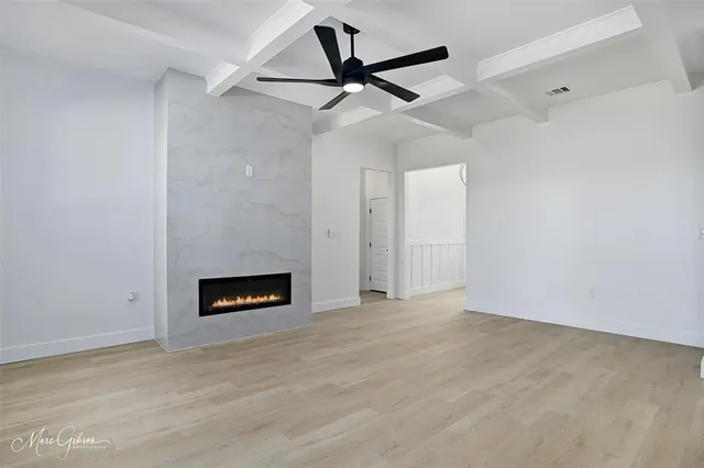 a view of an empty room with a fireplace and a ceiling fan