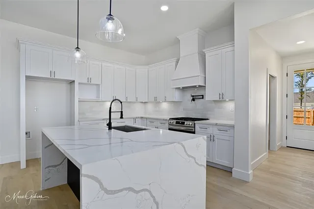 a kitchen with stainless steel appliances granite countertop a sink a stove a refrigerator and island with wooden floor