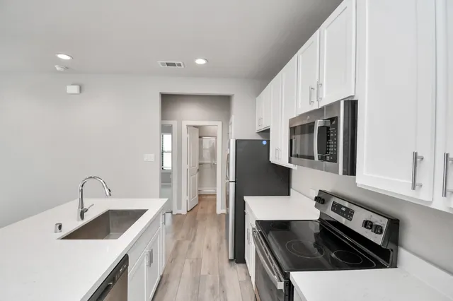 a view of kitchen with stainless steel appliances refrigerator stove microwave and cabinets