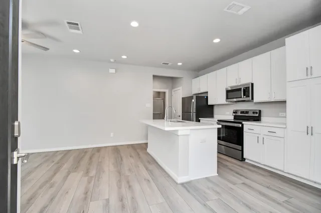 a kitchen with kitchen island white cabinets and stainless steel appliances