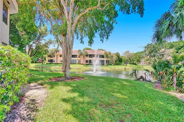 a view of a house with a big yard and palm trees