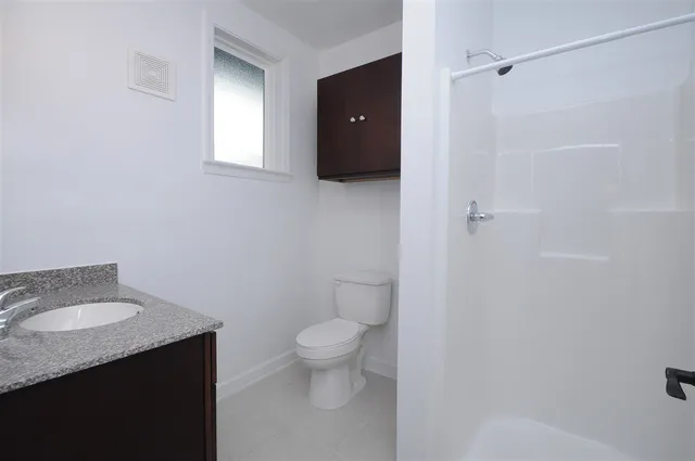 a bathroom with a granite countertop toilet and sink