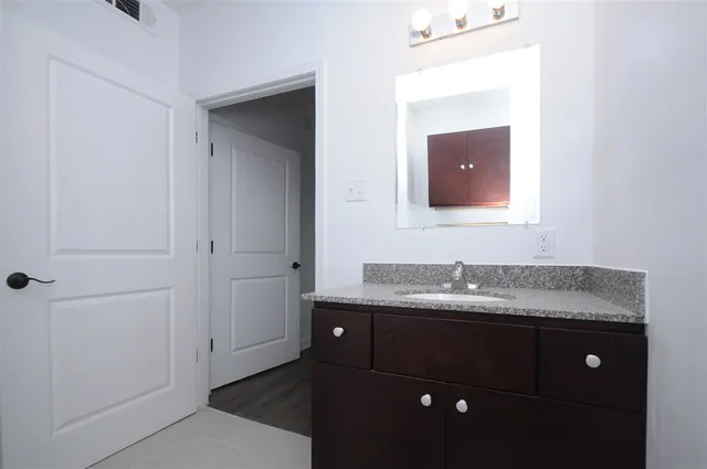 a bathroom with a granite countertop sink and a mirror