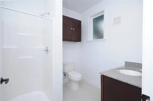 a bathroom with a granite countertop sink toilet and shower