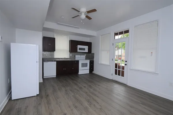 a kitchen with stainless steel appliances granite countertop a refrigerator a sink dishwasher a stove and white countertops with wooden floor