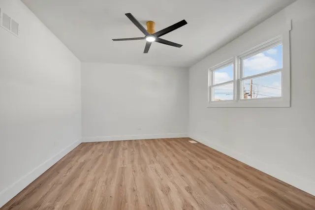 an empty room with a window and a ceiling fan