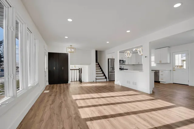 a view of an empty room with kitchen and window