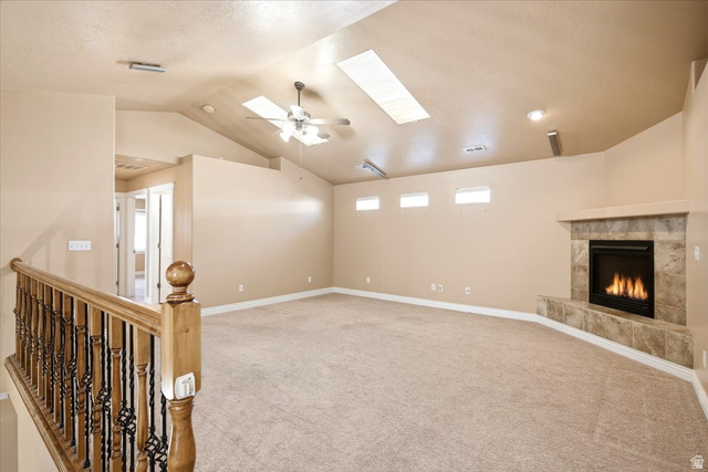 1089 West 2325th Street North Layton, UT 84041 - Photo 14 of 40 Spacious room featuring vaulted ceilings with skylights, a ceiling fan, and a gas fireplace with a tiled surround
