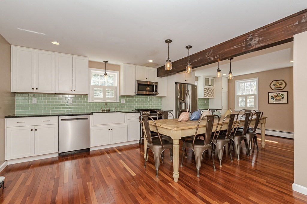12 Lakin Road Brookline, NH 03033 - Photo 10 of 14 a open kitchen with stainless steel appliances granite countertop a stove a refrigerator a kitchen island a dining table and chairs with wooden floor