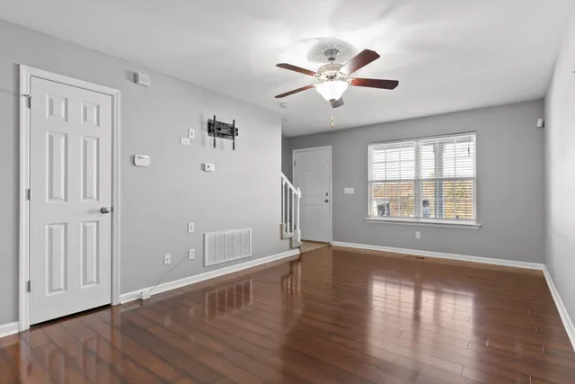 a view of an empty room with wooden floor and a window