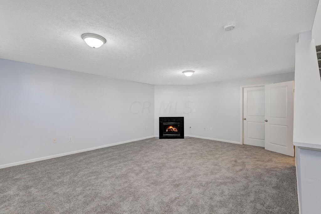 6345 Needletail Road, Unit 24634 Columbus, OH 43230 - Photo 27 of 58 • New gray carpet ~ 2021 • Gray painted walls • Egress window • Two ceiling lights • Corner gas fireplace • 2” blinds