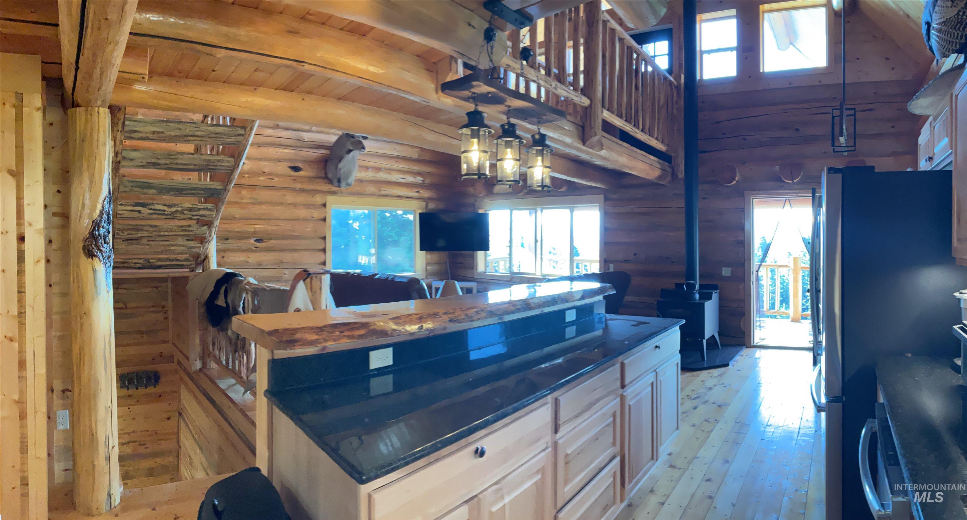 625 Rhett Creek Road Elk City, ID 83525 - Photo 21 of 48 Expansive wood-plank deck featuring a natural wood railing, a black exterior door with window panes, and a mounted lantern-style light fixture