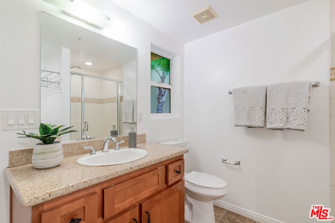 5521 Kester Avenue, Unit 7 Sherman Oaks, CA 91411 - Photo 30 of 45 a bathroom with a granite countertop sink a toilet and a mirror