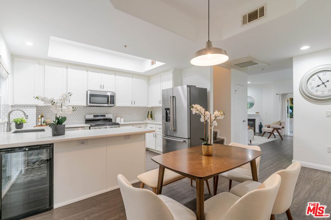 5521 Kester Avenue, Unit 7 Sherman Oaks, CA 91411 - Photo 7 of 45 a kitchen with stainless steel appliances a dining table chairs stove refrigerator and cabinets