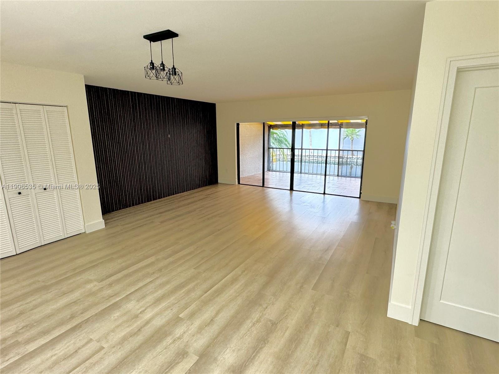 16401 Bridge End Road, Unit 16401 Miami Lakes, FL 33014 - Photo 6 of 19 a view of an empty room with wooden floor and a window