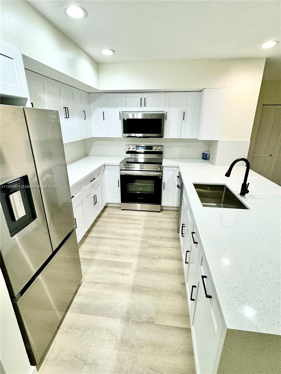 16401 Bridge End Road, Unit 16401 Miami Lakes, FL 33014 - Photo 10 of 19 a kitchen with granite countertop a sink and a stove top oven