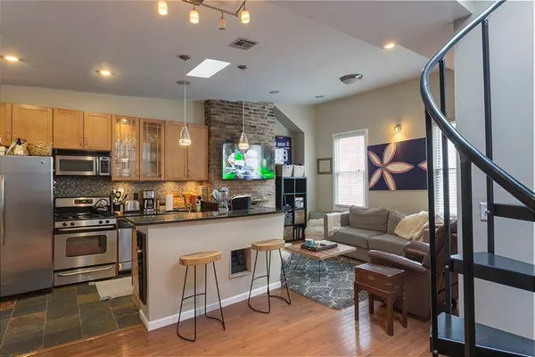 a kitchen with stainless steel appliances granite countertop a stove top oven a sink dishwasher a dining table and chairs with wooden floor