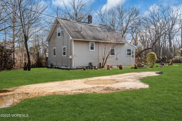 a view of a barn in front of a house with plants and large tree
