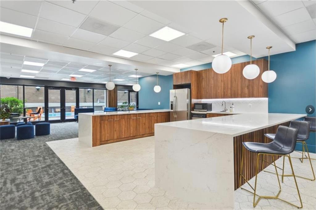 620 Peachtree Street Northeast, Unit 901 Atlanta, GA 30308 - Photo 5 of 19 a large kitchen with stainless steel appliances kitchen island granite countertop a large kitchen island a stove a sink a dining table and chairs with the large windows