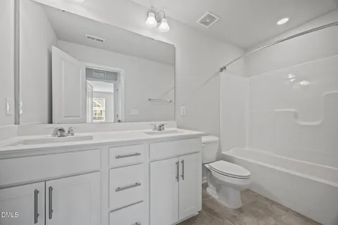 a bathroom with a toilet a sink a mirror a bathtub and vanity