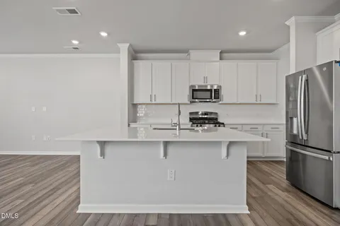 a kitchen with kitchen island white cabinets and stainless steel appliances