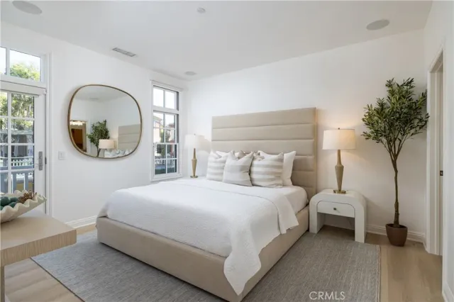 a bedroom with a bed a potted plant and a large window