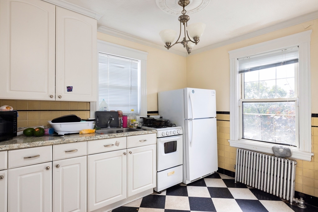 99 Franklin Street Lynn, MA 01902 - Photo 9 of 11 a kitchen with granite countertop cabinets a stove a sink and a window