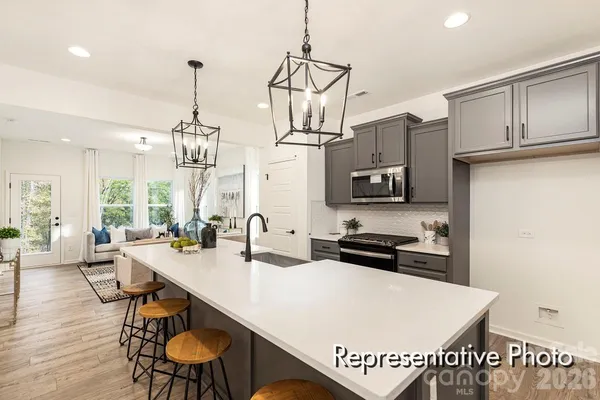 a kitchen with stainless steel appliances a sink a stove a refrigerator white cabinets and wooden floor