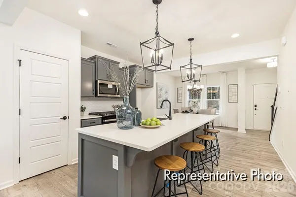 a kitchen with stainless steel appliances a sink a stove a refrigerator cabinets and living room view