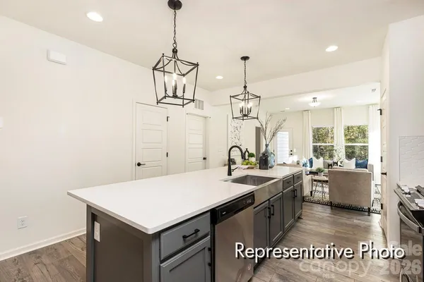 a kitchen with a stove a sink and wooden floor