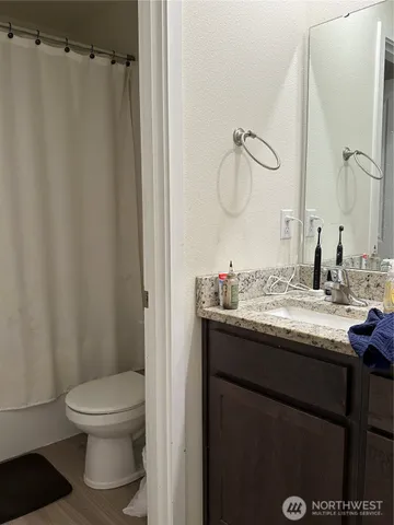 a bathroom with a granite countertop sink toilet and a mirror