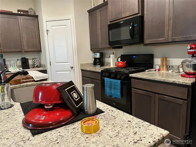 a kitchen with stainless steel appliances kitchen island granite countertop a stove a sink dishwasher and microwave with wooden floor