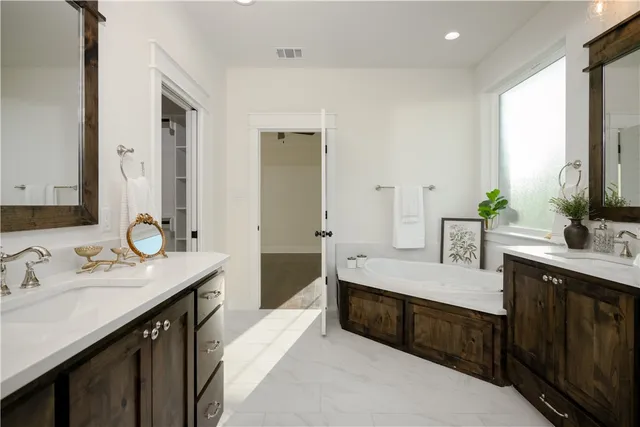 a spacious bathroom with a double vanity sink a large mirror and a bathtub