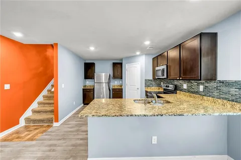 a view of kitchen with kitchen island granite countertop stainless steel appliances stove sink and cabinets