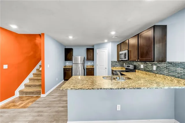 a view of kitchen with kitchen island granite countertop stainless steel appliances stove sink and cabinets