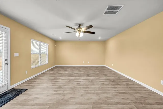 a view of an empty room with chandelier fan and a window