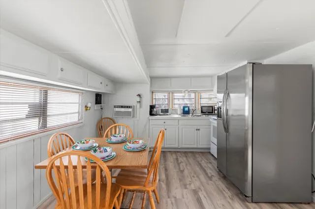 a kitchen with stainless steel appliances granite countertop a dining table chairs wooden floor and a window