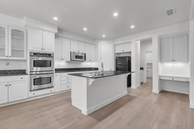 a large kitchen with stainless steel appliances granite countertop a lot of counter space and wooden floor