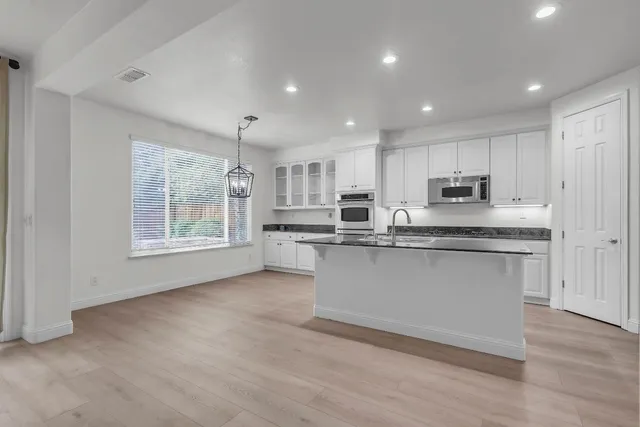 a kitchen with granite countertop white cabinets stainless steel appliances and sink