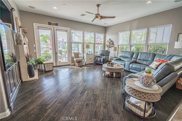 a living room with furniture a chandelier fan and a large window