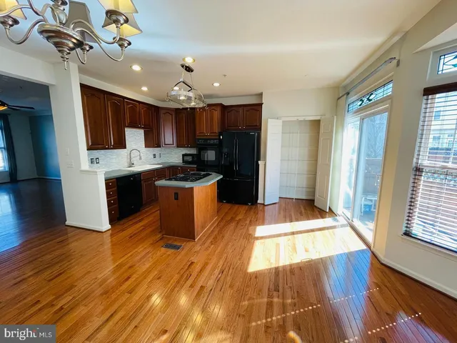 a large kitchen with stainless steel appliances kitchen island granite countertop a stove a refrigerator a sink dishwasher and a cabinets with wooden floor