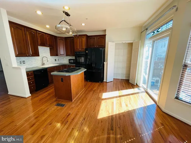 a kitchen with stainless steel appliances granite countertop a stove a sink dishwasher and a refrigerator with wooden floor