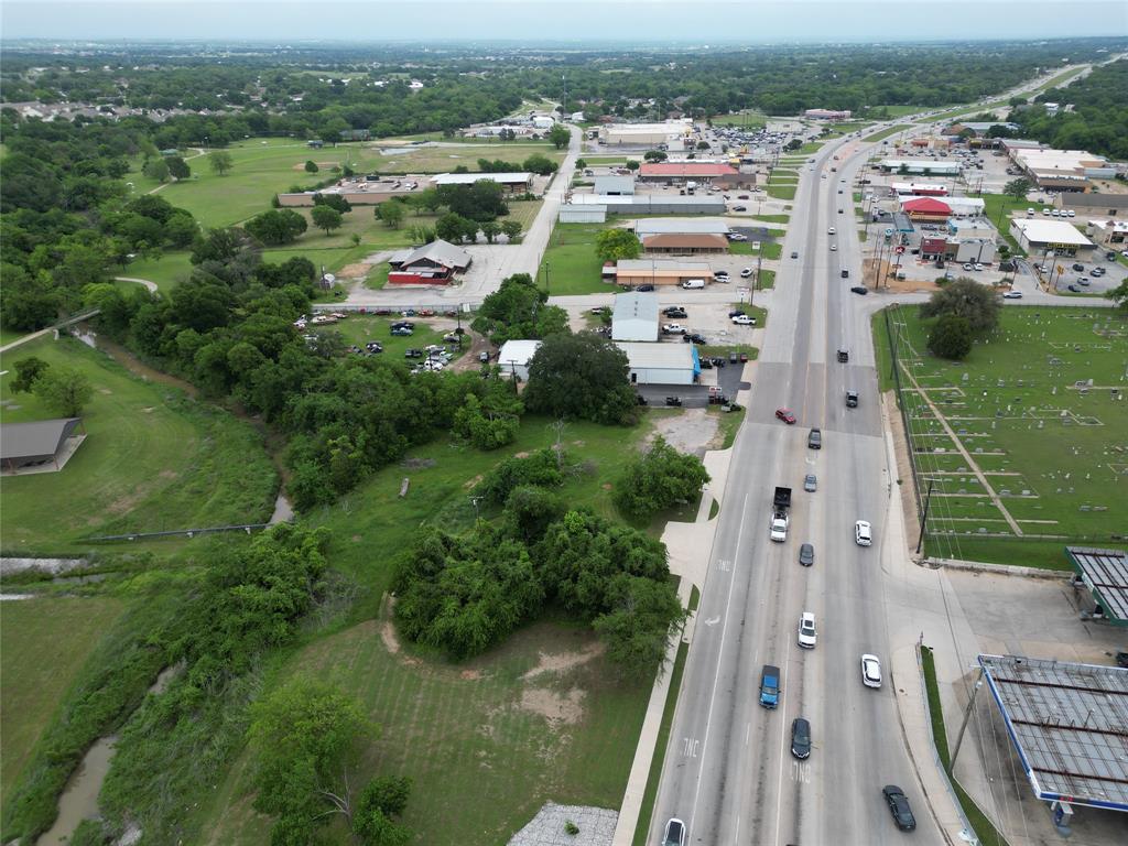 116 East Highway 199 Springtown, TX 76082 - Photo 4 of 15 Aerial perspective highlighting a multi-lane roadway with active traffic, adjacent commercial structures, and extensive green spaces