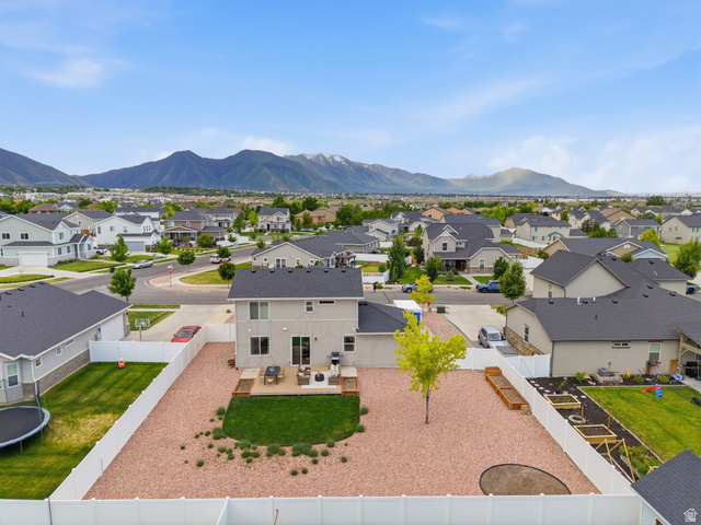 834 West 1050th Street South Springville, UT 84663 - Photo 25 of 26 Rear exterior of a two-story residence featuring a ground-level deck, a fenced yard with gravel and a lawn area, and a mature tree